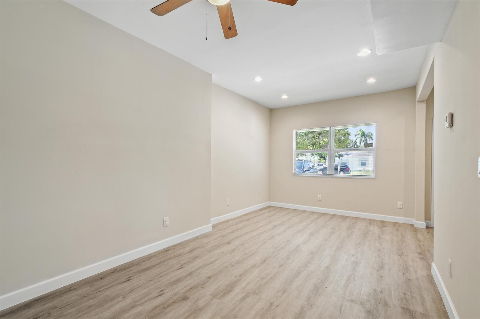 An empty room features light-colored walls, wood-look flooring, a ceiling fan, and a window — 627 Bunker Road, West Palm Beach FL 33405, WEST PALM BEACH, FL