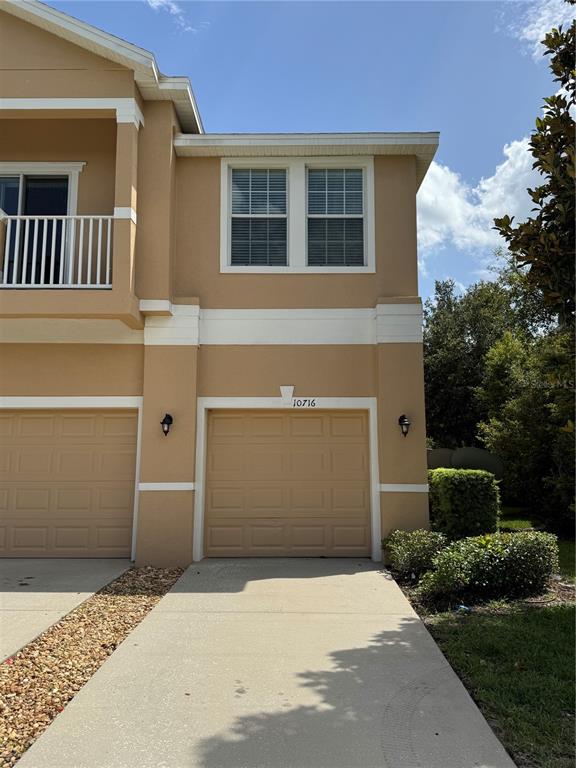 A two-story tan townhouse with a single-car garage and a second-floor balcony — 10716 DAWSON LILY WAY UNIT 39A, ORLANDO, FL