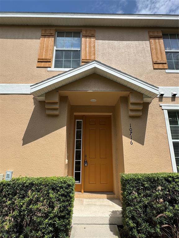 The exterior of a two-story home features a tan stucco facade, brown shutters, and a porch — 10716 DAWSON LILY WAY UNIT 39A, ORLANDO, FL
