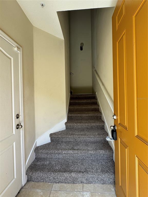 An interior view shows a carpeted staircase leading upward from a tiled entryway — 10716 DAWSON LILY WAY UNIT 39A, ORLANDO, FL