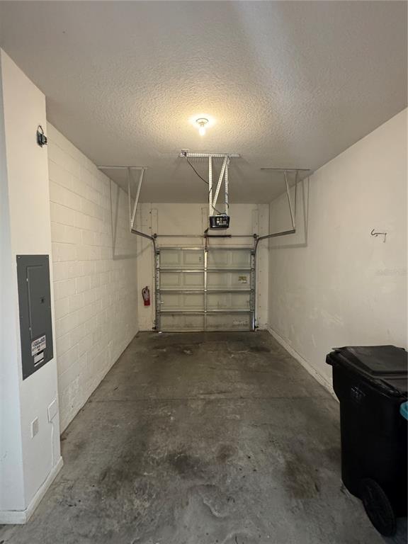 An empty residential garage with a concrete floor, white block walls, and a ceiling-mounted opener — 10716 DAWSON LILY WAY UNIT 39A, ORLANDO, FL