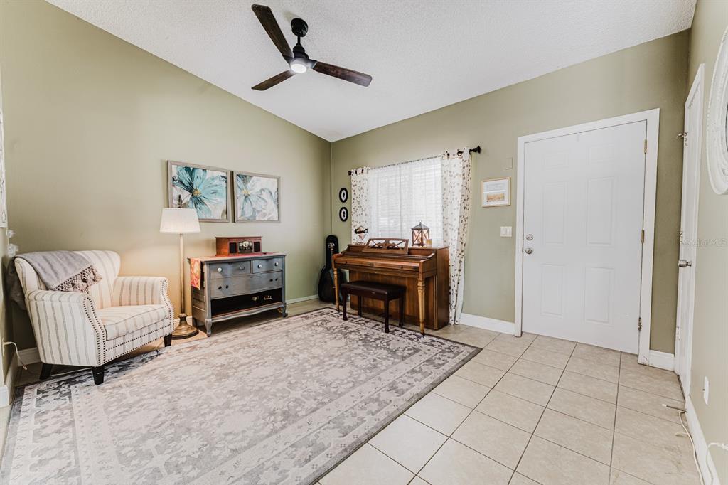 A living room features a piano, an armchair, a dresser, and a large area rug — 212 SUMMERSET DRIVE, APOPKA, FL
