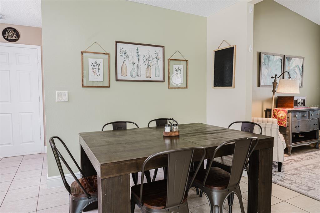 A dining room features a dark wood table, metal chairs, and botanical wall art — 212 SUMMERSET DRIVE, APOPKA, FL