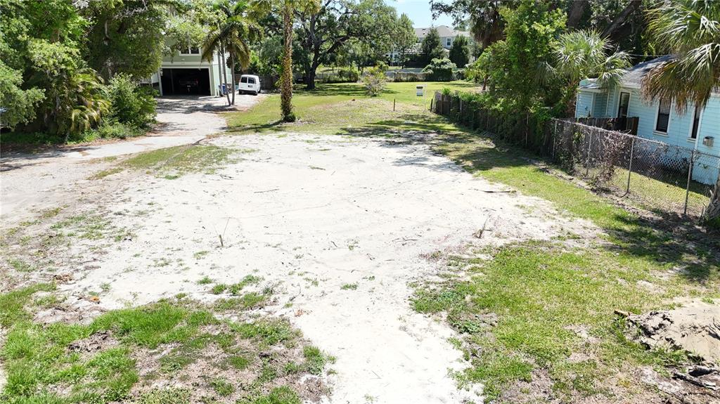 An elevated view shows a sandy, cleared residential lot bordered by trees and neighboring houses — 290 ORANGE STREET, PALM HARBOR, FL