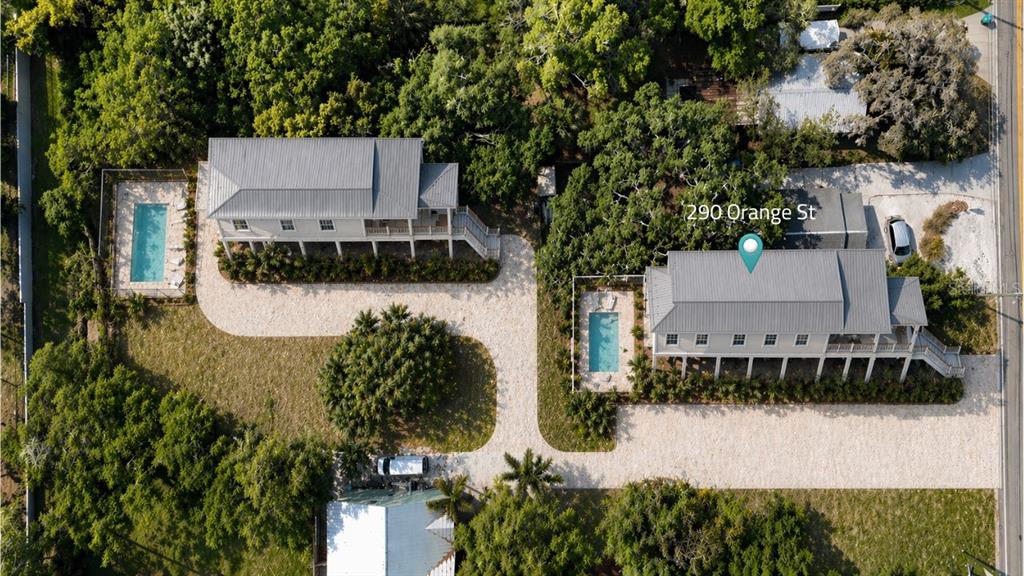 An aerial view shows two elevated houses with metal roofs, private pools, and gravel driveways — 290 ORANGE STREET, PALM HARBOR, FL