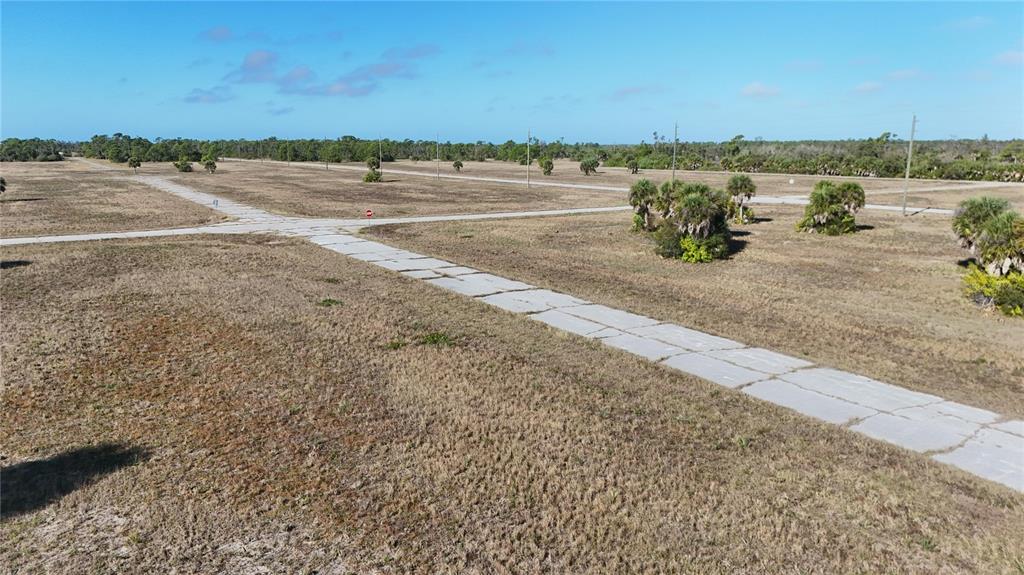 An aerial view shows a vacant, grassy lot with paved roads intersecting in a rural area — 14381 SWORDFISH COURT, PLACIDA, FL