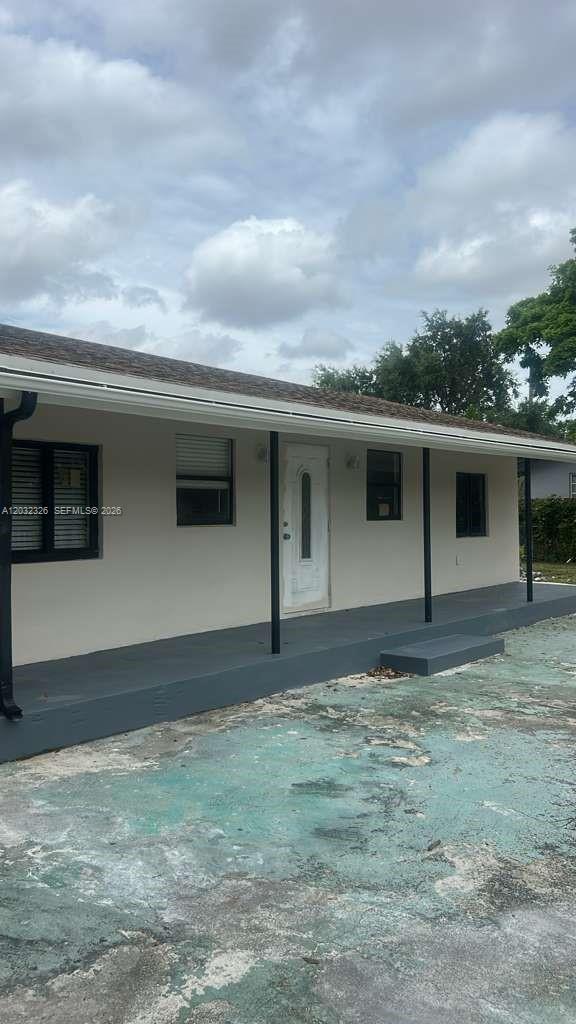 The exterior of a single-story house features a covered porch and a white front door — 2467 NW 103rd St, Miami FL 33147, MIAMI, FL