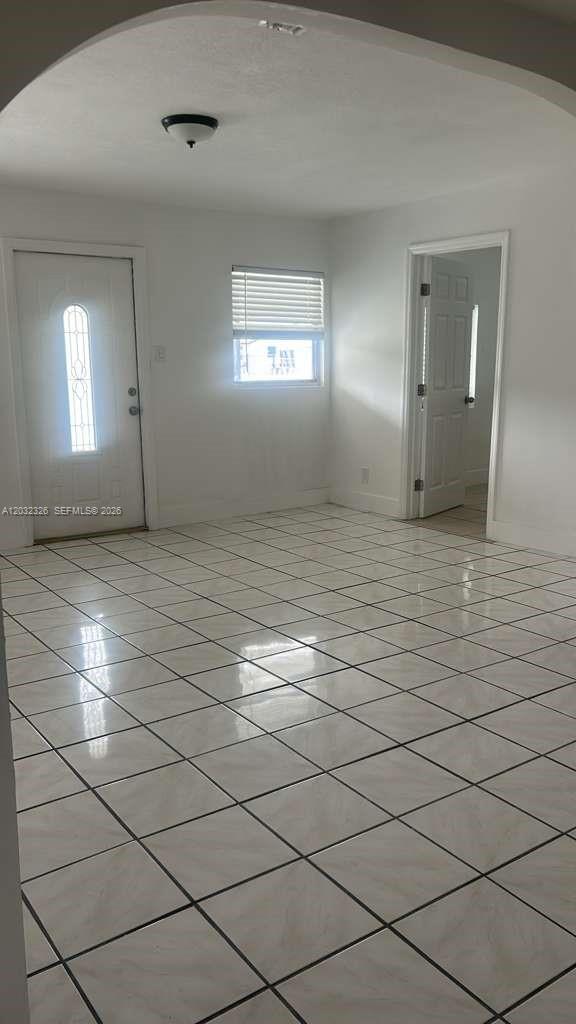 A room with white walls, a tiled floor, a front door, and an arched entryway — 2467 NW 103rd St, Miami FL 33147, MIAMI, FL