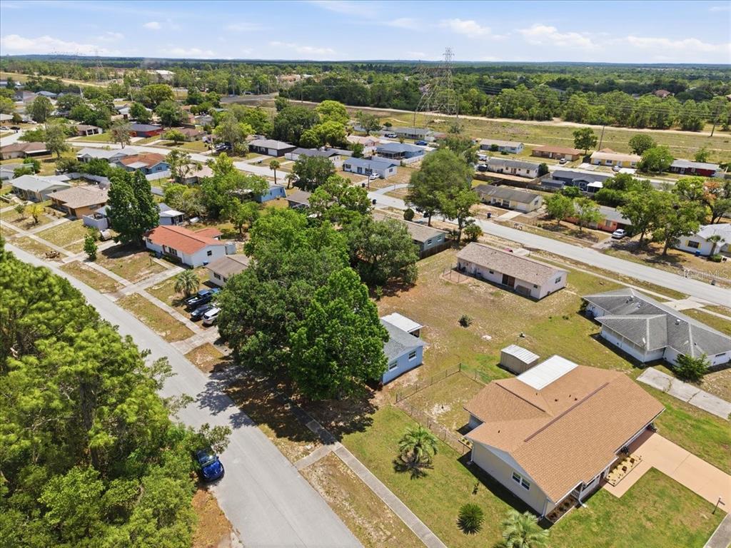 An aerial view shows a suburban neighborhood with single-story houses, trees, and paved streets — 12452 EDDINGTON ROAD, SPRING HILL, FL