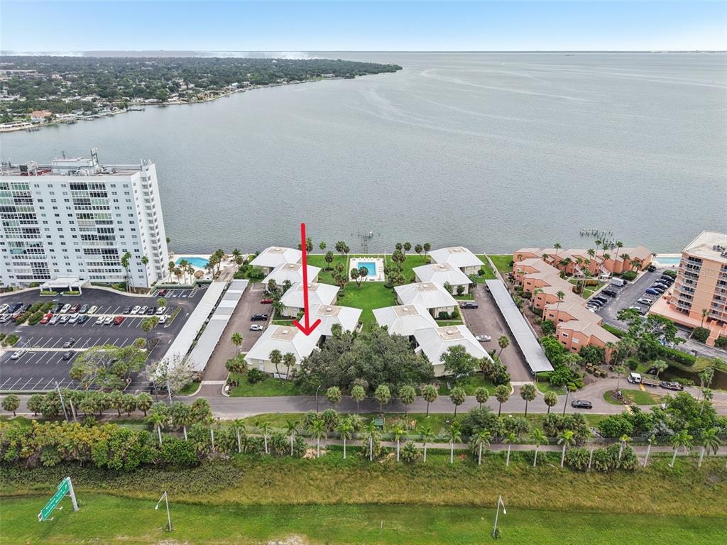 An aerial view shows a waterfront condominium complex with a pool and parking lots — 7300 SUNSHINE SKYWAY LANE S UNIT 202, ST PETERSBURG, FL