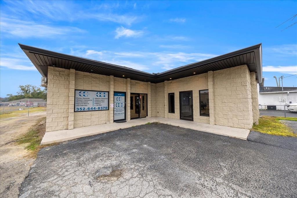 A single-story commercial building with tan block walls and a dark, overhanging roof — 2733 SE 58TH AVENUE, OCALA, FL