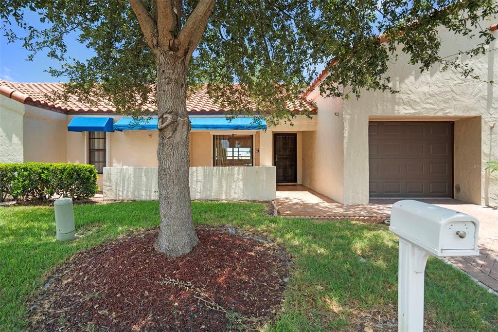 A single-story house with a tiled roof, blue awnings, a front patio, and a garage — 4109 89TH AVENUE N, PINELLAS PARK, FL