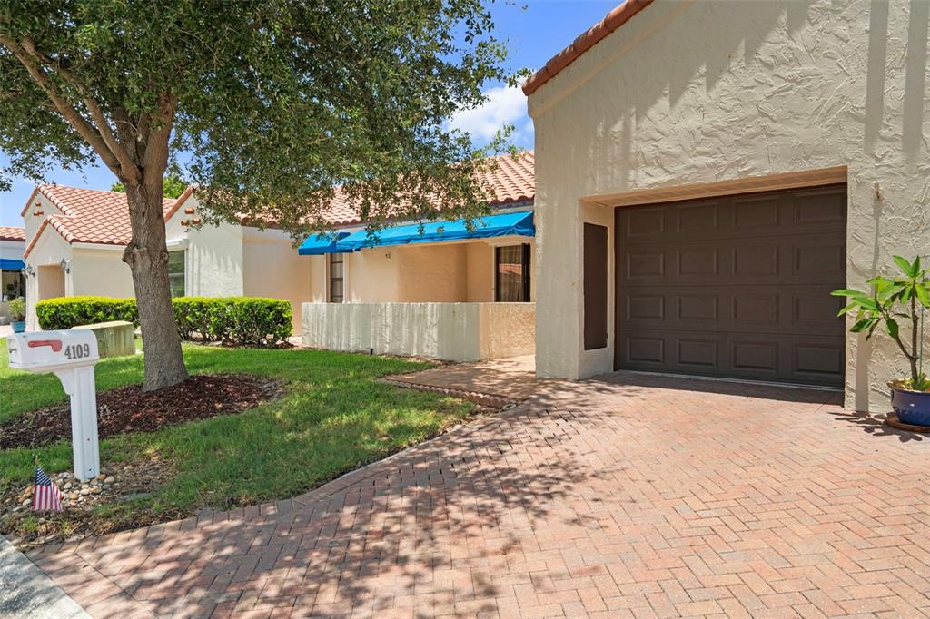 A single-story house with a brick driveway, a brown garage door, and a blue awning — 4109 89TH AVENUE N, PINELLAS PARK, FL