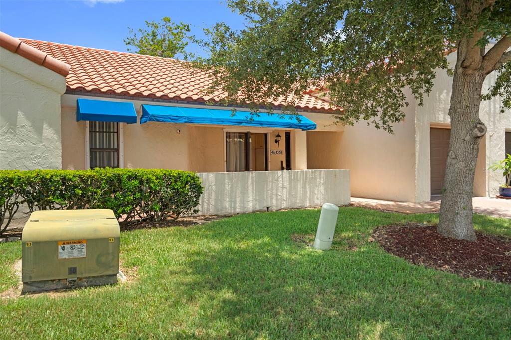 A single-story residential unit features a tiled roof, blue awnings, and a small patio — 4109 89TH AVENUE N, PINELLAS PARK, FL