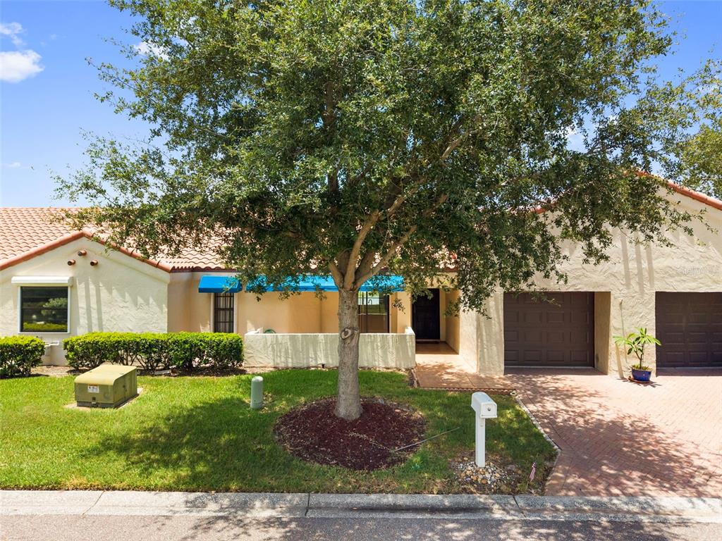 A single-story house with a tile roof, a large tree, and a brick driveway — 4109 89TH AVENUE N, PINELLAS PARK, FL