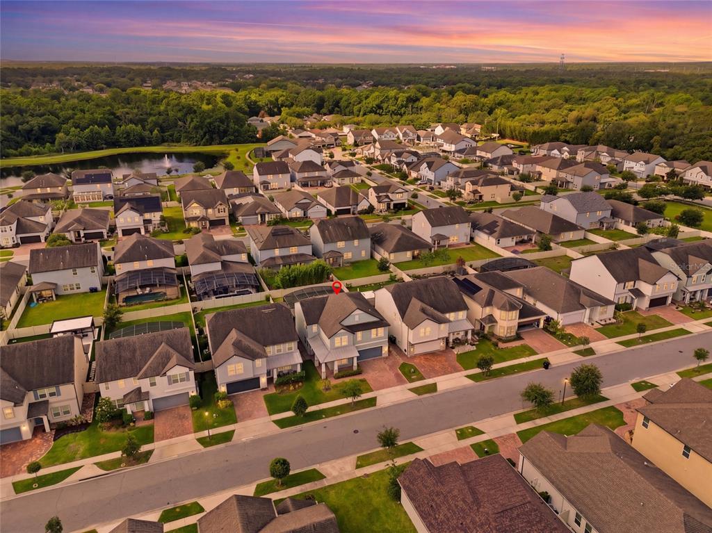 An aerial view shows a suburban neighborhood with many single-family homes and a small lake — 1369 BRISTOL OAKS WAY, ORLANDO, FL