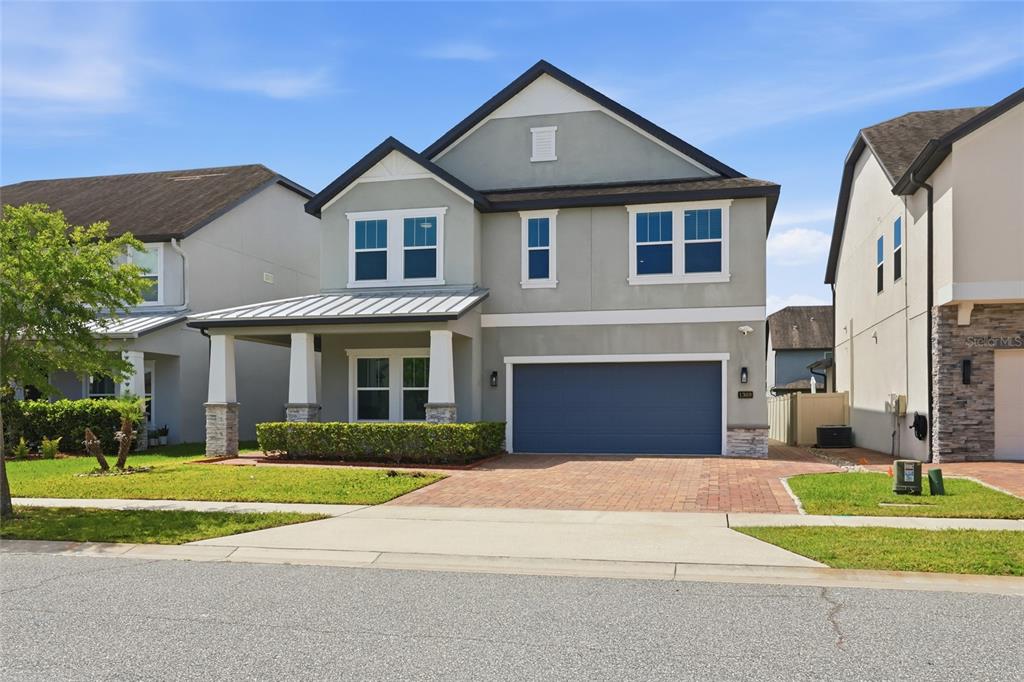 A two-story house with a gray stucco exterior, a front porch, and a blue garage door — 1369 BRISTOL OAKS WAY, ORLANDO, FL