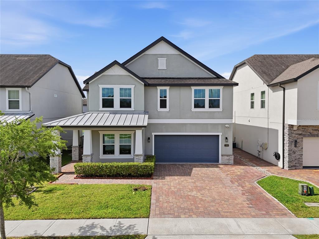 A two-story house with a gray exterior, metal-roofed porch, and a brick paver driveway — 1369 BRISTOL OAKS WAY, ORLANDO, FL