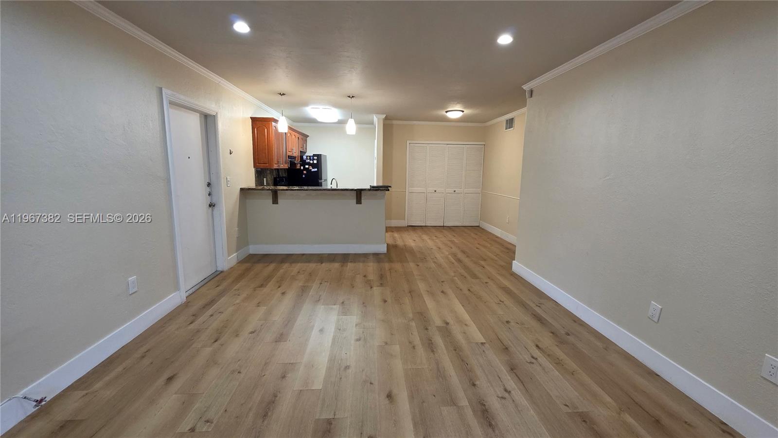 An open-concept living area features light wood-look flooring, a breakfast bar, and a kitchen — 7829 Miller Dr # B104, Miami FL 33155, MIAMI, FL