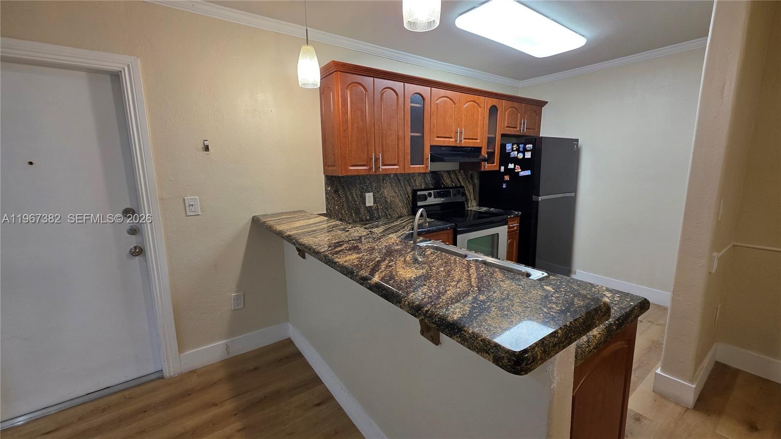 A kitchen features wood cabinets, granite countertops, a breakfast bar, and black appliances — 7829 Miller Dr # B104, Miami FL 33155, MIAMI, FL