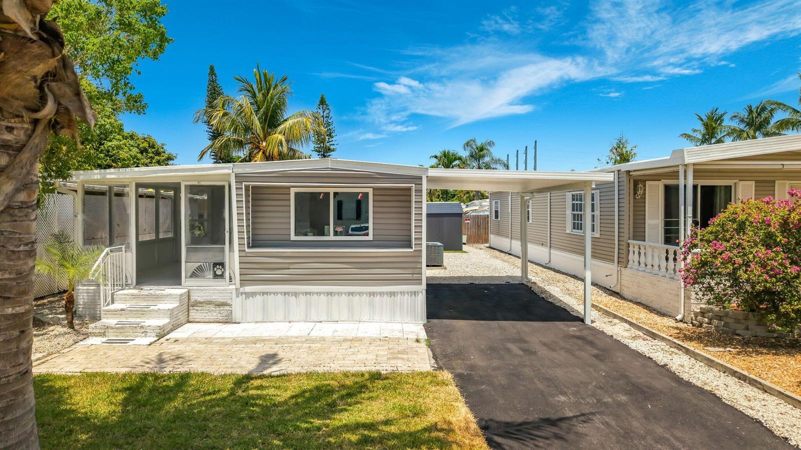 A manufactured home with a gray exterior, a screened-in porch, and an attached carport — 2611 E Marina Drive, Dania Beach FL 33312, DANIA BEACH, FL