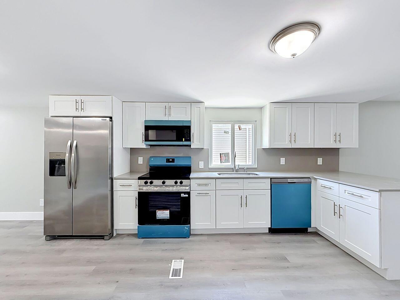 A kitchen with white cabinets, stainless steel appliances, and light wood-look flooring — 2611 E Marina Drive, Dania Beach FL 33312, DANIA BEACH, FL