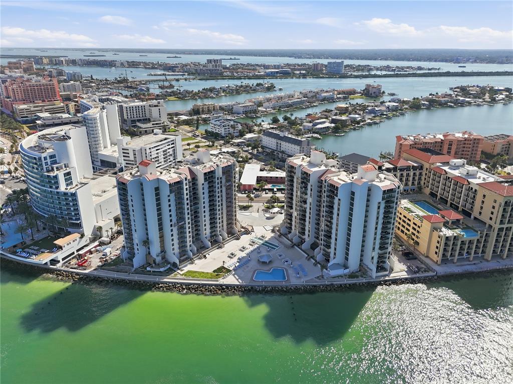 An aerial view of high-rise waterfront condominiums with pools along a coastal bay — 450 S GULFVIEW BOULEVARD UNIT 301, CLEARWATER BEACH, FL