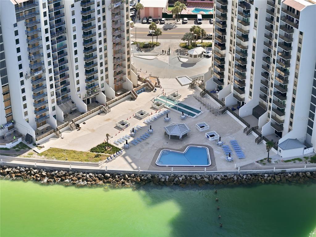 An aerial view shows a swimming pool and patio area between two high-rise residential buildings — 450 S GULFVIEW BOULEVARD UNIT 301, CLEARWATER BEACH, FL