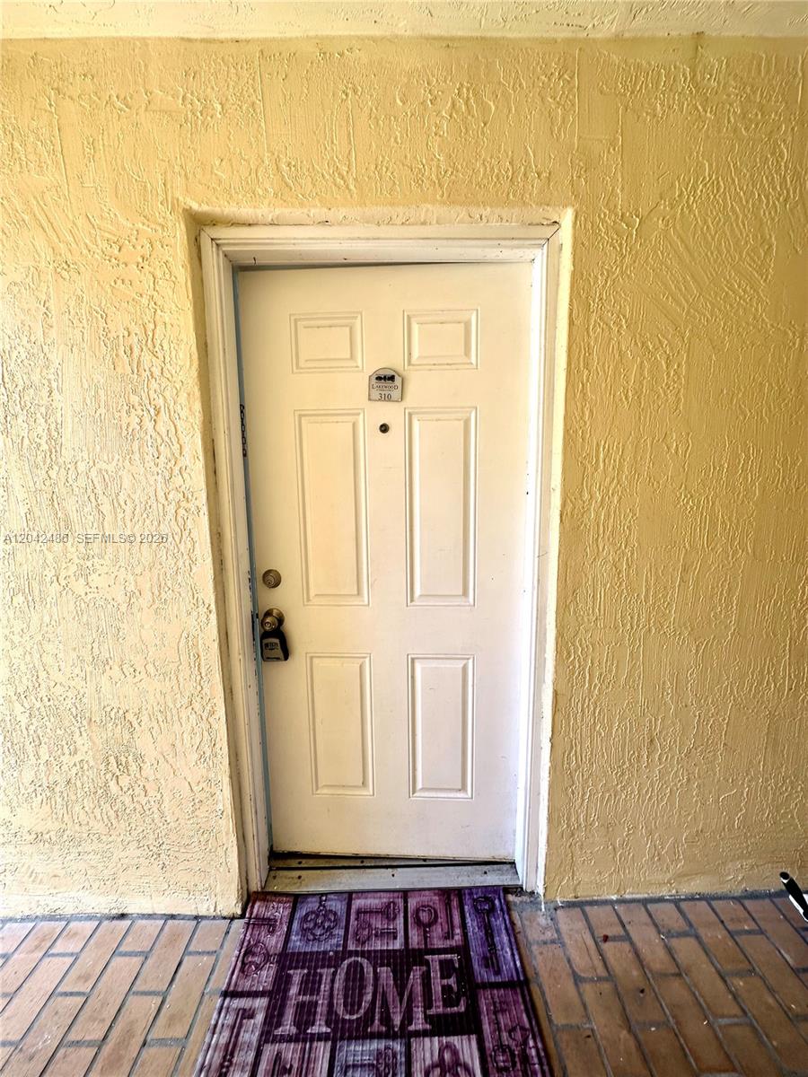 A white front door with a lockbox and a purple welcome mat on a patio — 3630 N 56th Ave # 310, Hollywood FL 33021, HOLLYWOOD, FL