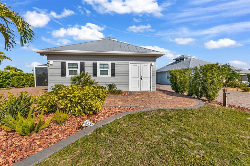 A gray detached garage with a metal roof and double doors sits on a paved lot — 8306 SW SAND CRANE LOT 87 CIRCLE, ARCADIA, FL
