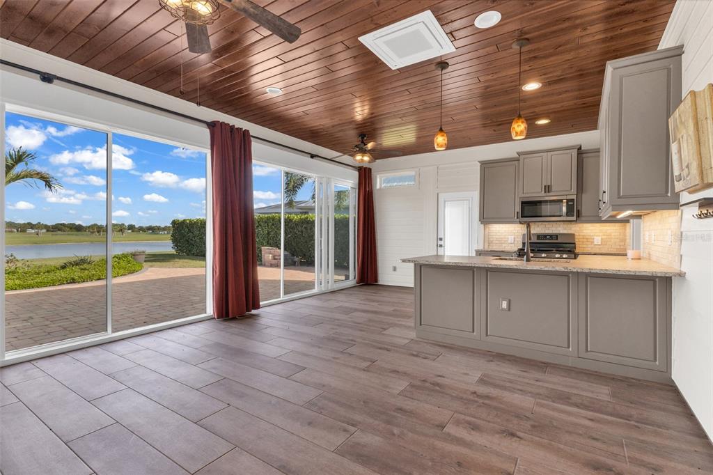 A kitchen and living area with a wood-paneled ceiling, tile floors, and sliding glass doors — 8306 SW SAND CRANE LOT 87 CIRCLE, ARCADIA, FL
