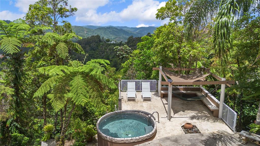 An outdoor patio features a hot tub, two lounge chairs, and a shaded seating area — PR-184 GUAVATE, CAYEY, PR