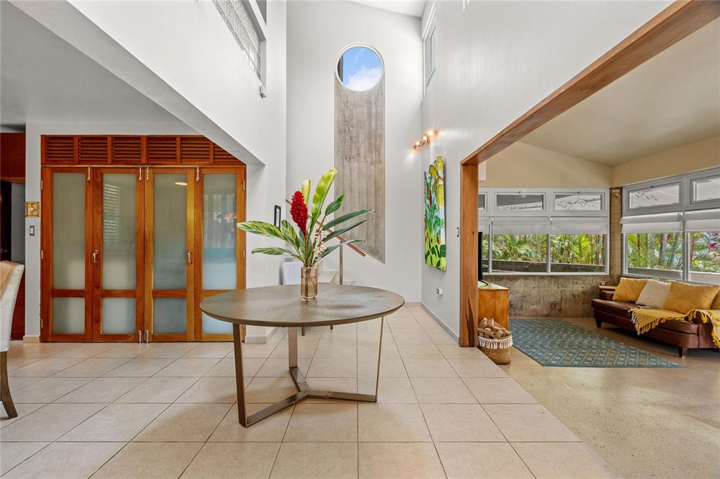 A round table sits in a bright, high-ceilinged foyer with tile floors and concrete accents — PR-184 GUAVATE, CAYEY, PR