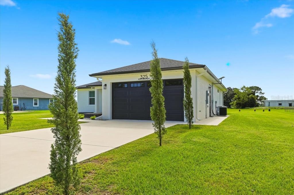 A white single-story house with a two-car garage sits on a grassy lot — 325 MONTE REAL BOULEVARD, SEBRING, FL