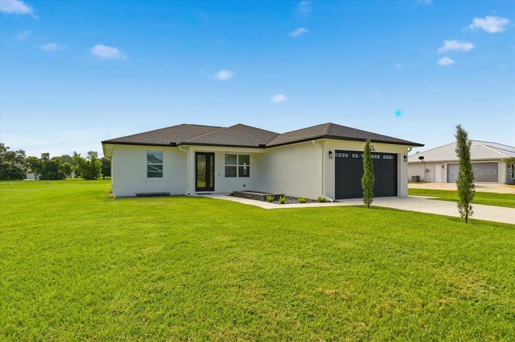 A single-story white house with a dark roof and a two-car garage — 325 MONTE REAL BOULEVARD, SEBRING, FL