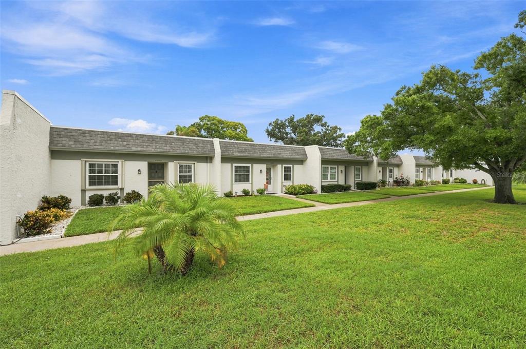 A row of single-story residential units with white stucco walls and gray shingled roofs — 4651 LAKE VILLA DRIVE, CLEARWATER, FL