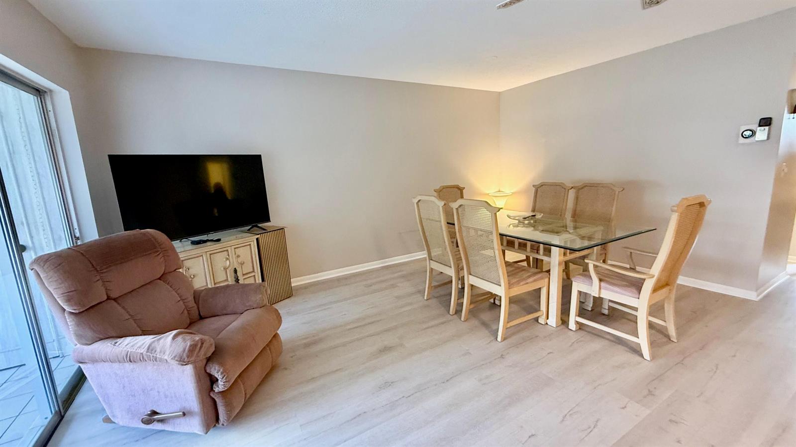 A living and dining area features light wood-look flooring, a recliner, and a glass-topped table — 705 Lori Drive # 209, Palm Springs FL 33461, PALM SPRINGS, FL