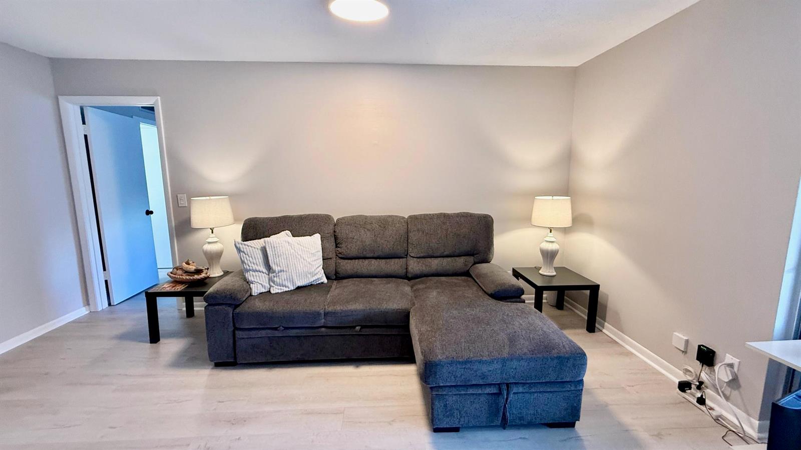 A gray sectional sofa sits between two end tables with lamps in a living room — 705 Lori Drive # 209, Palm Springs FL 33461, PALM SPRINGS, FL