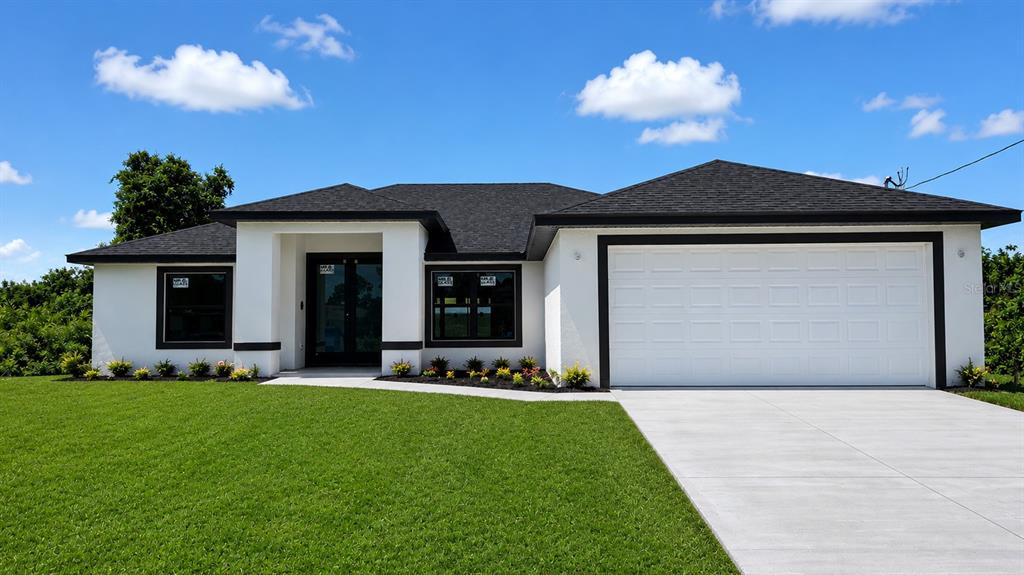 A single-story house with white stucco walls, a dark roof, and a two-car garage — 3205 12TH STREET SW, LEHIGH ACRES, FL