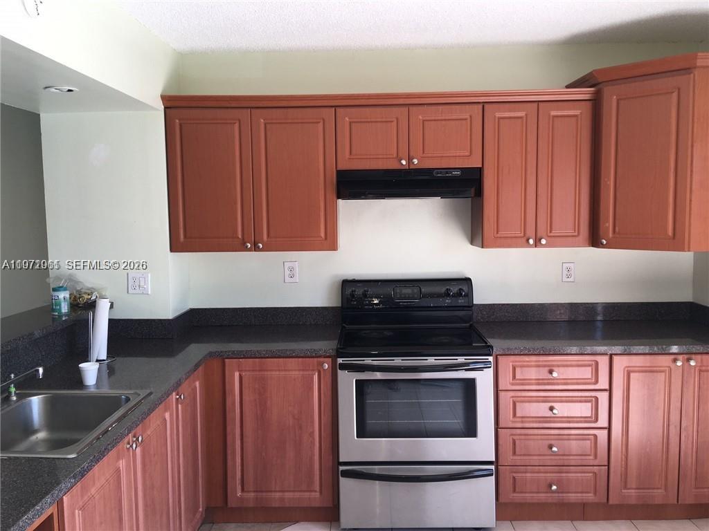 A kitchen features wood cabinets, dark countertops, and stainless steel appliances — 2162 W 60th St # 14208, Hialeah FL 33016, HIALEAH, FL