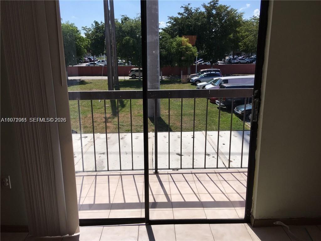 A sliding glass door opens onto a balcony overlooking a parking lot and trees — 2162 W 60th St # 14208, Hialeah FL 33016, HIALEAH, FL