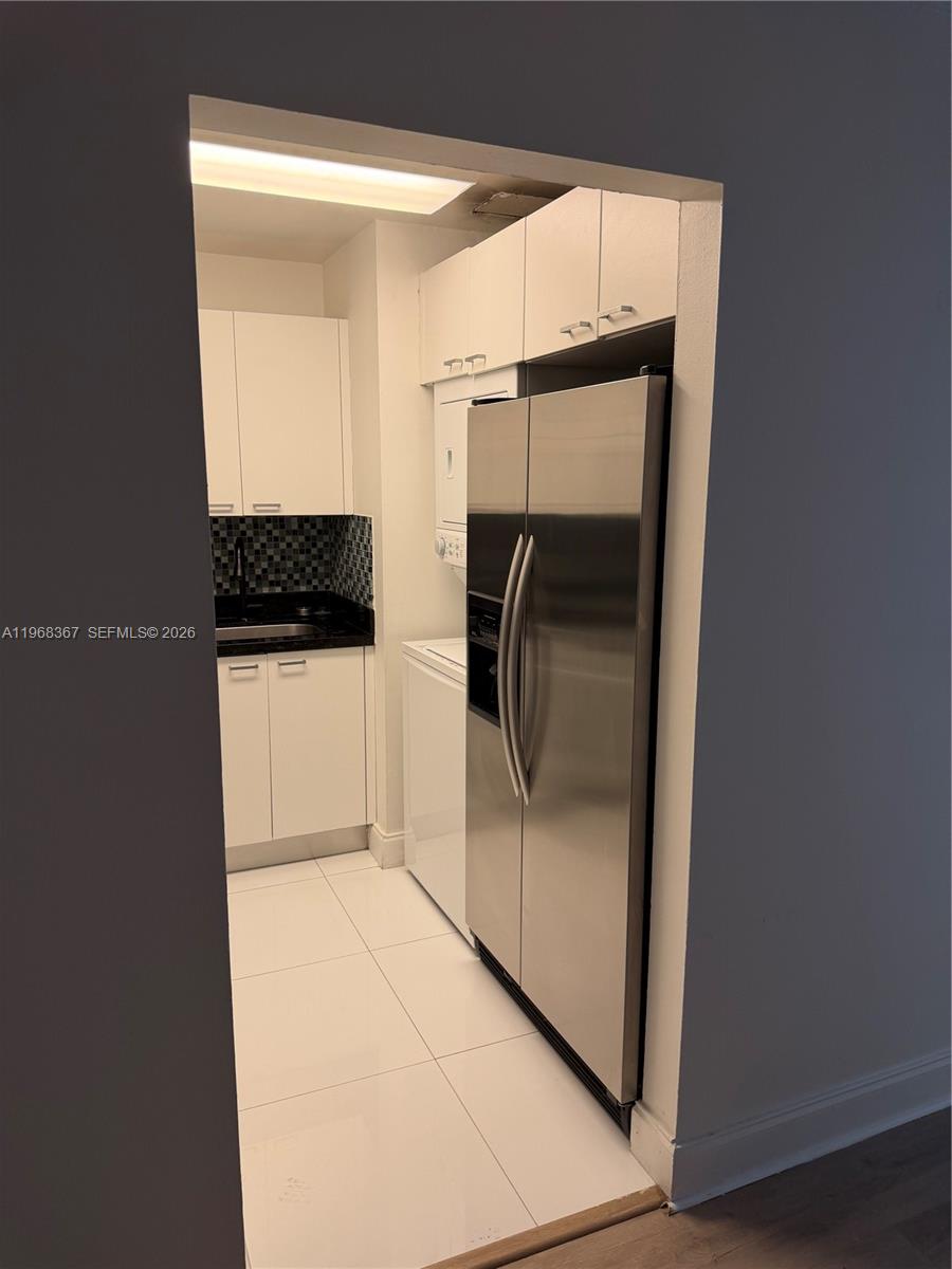 A small kitchen features white cabinets, stainless steel appliances, and a stacked laundry unit — 7925 SW 86th St # 923, Miami FL 33143, MIAMI, FL