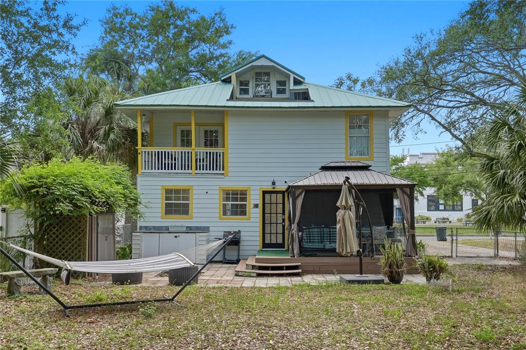 The exterior of a two-story house features light blue siding, yellow trim, and a gazebo — 516 5TH AVENUE N, SAFETY HARBOR, FL