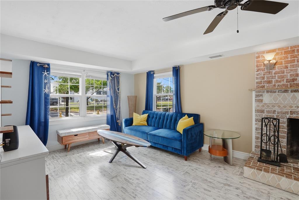 A living room features a blue sofa, a surfboard coffee table, and a brick fireplace — 516 5TH AVENUE N, SAFETY HARBOR, FL