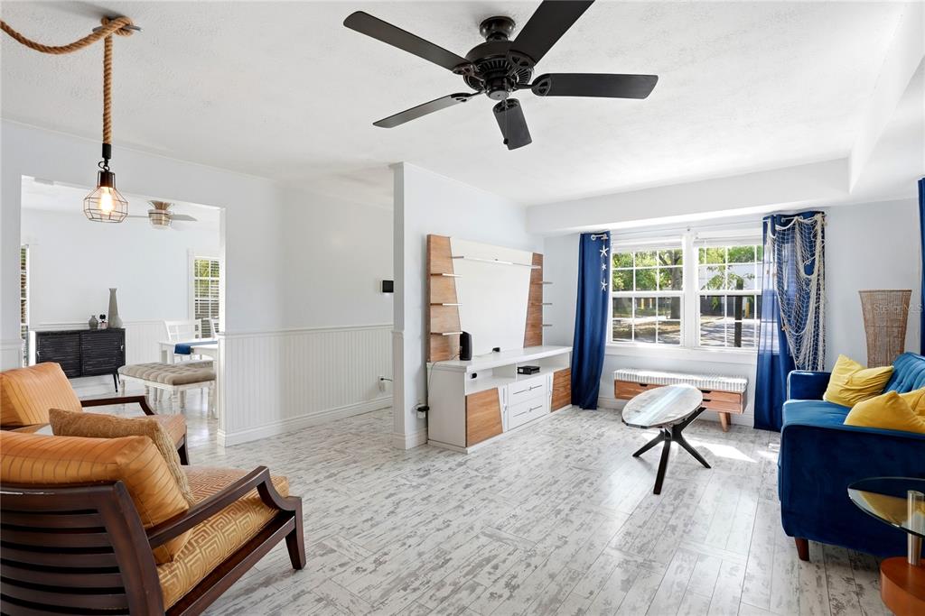 A living room features white wood-look tile floors, a ceiling fan, and blue and yellow furniture — 516 5TH AVENUE N, SAFETY HARBOR, FL
