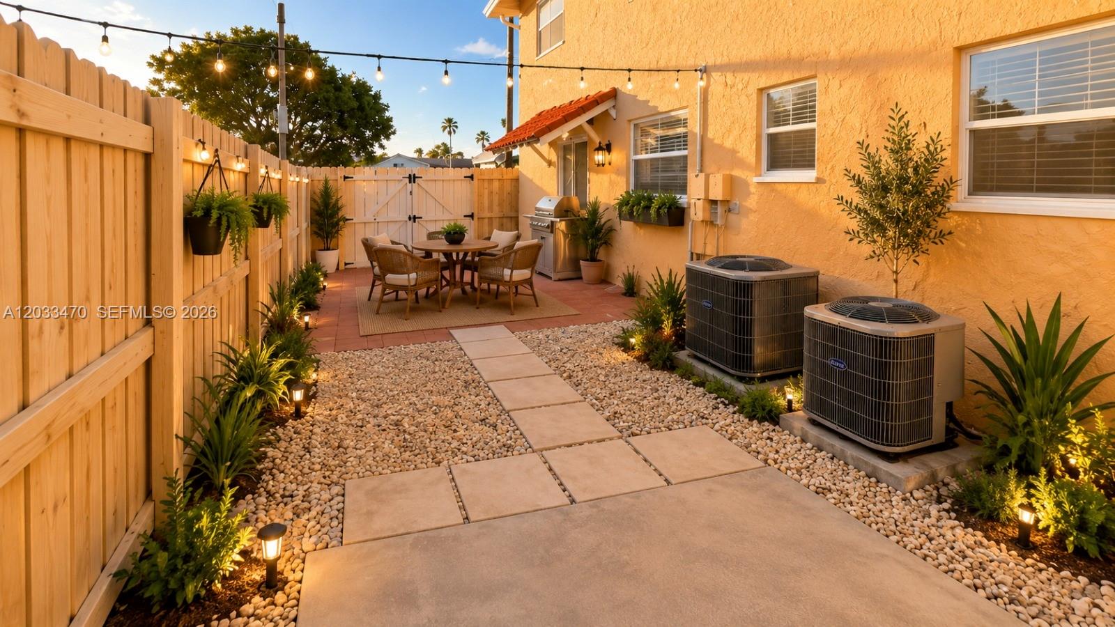 A fenced backyard features a patio with dining furniture, gravel landscaping, and two air conditioning units — 5461 W 24th Ave # 18, Hialeah FL 33016, HIALEAH, FL