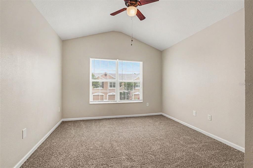 An empty bedroom with beige walls, tan carpeting, a ceiling fan, and a window — 26533 CASTLEVIEW WAY, WESLEY CHAPEL, FL