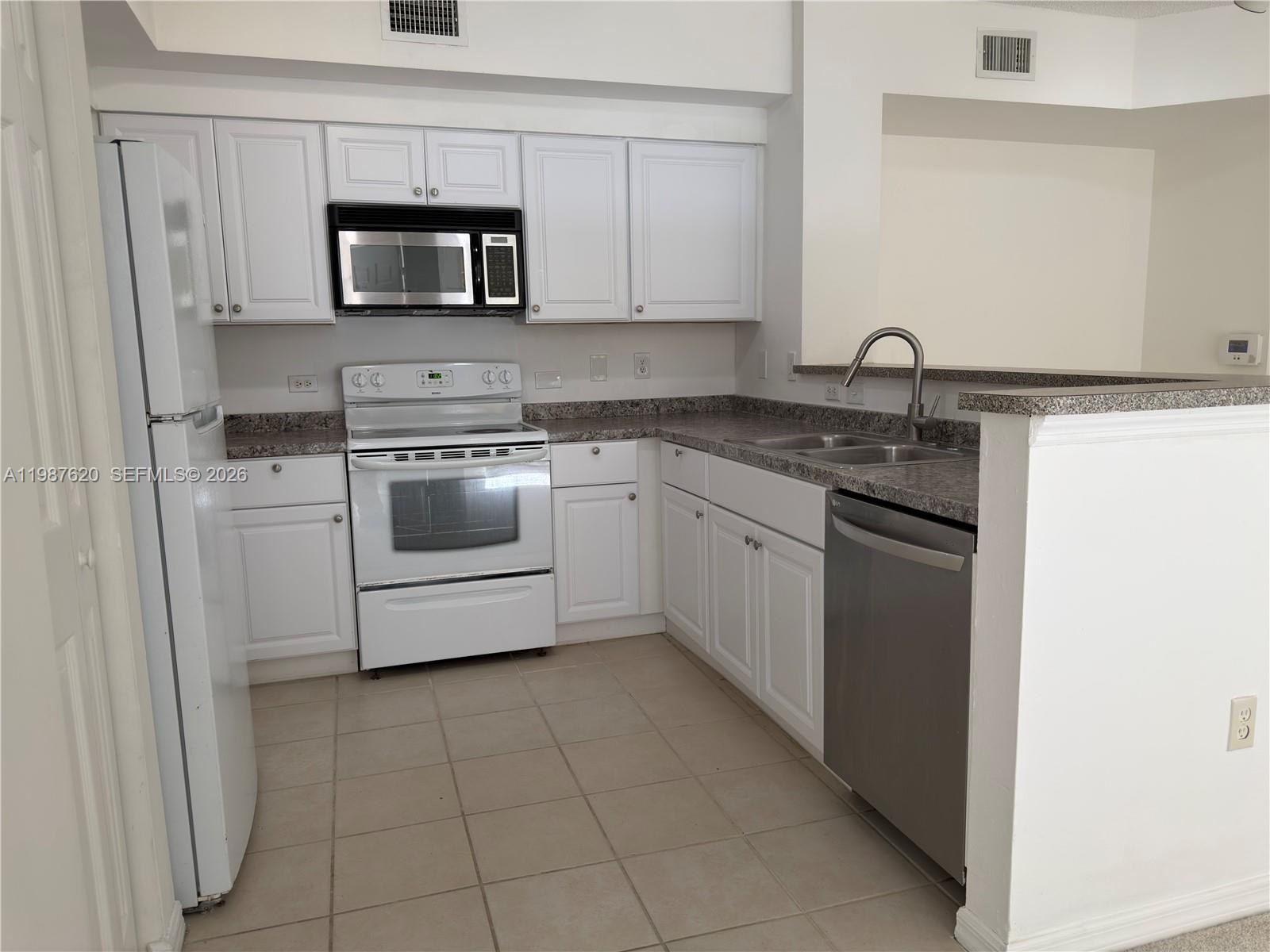 A kitchen features white cabinets, white appliances, a stainless steel dishwasher, and granite countertops — 2351 W Preserve Way # 104, Miramar FL 33025, MIRAMAR, FL