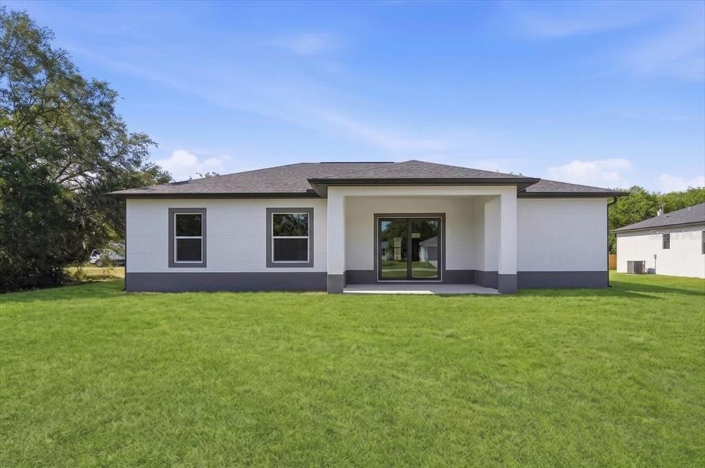 The exterior rear view of a single-story house with a covered patio and lawn — 2904 OLD STATE ROAD 64 W, AVON PARK, FL