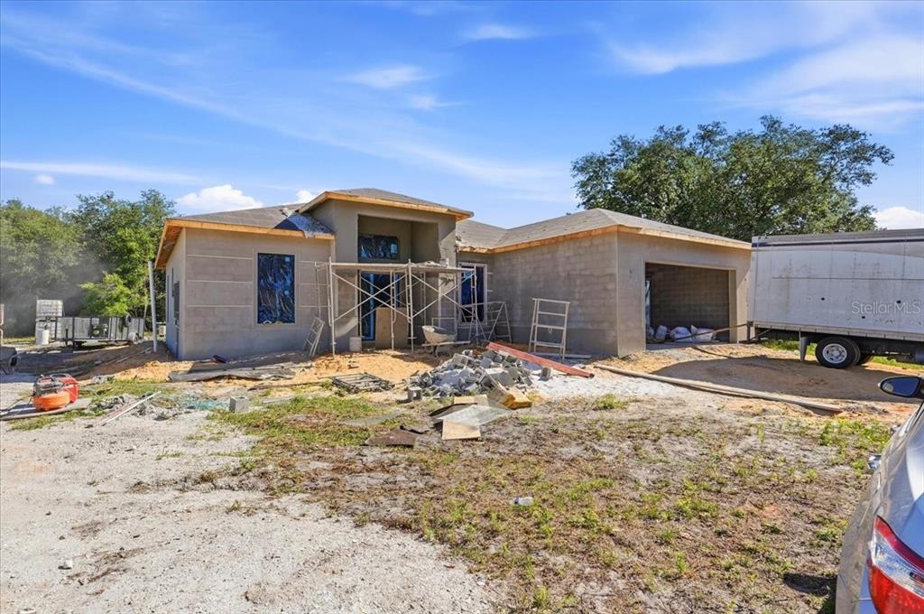 A single-story house under construction with a stucco exterior and an open garage — 2904 OLD STATE ROAD 64 W, AVON PARK, FL